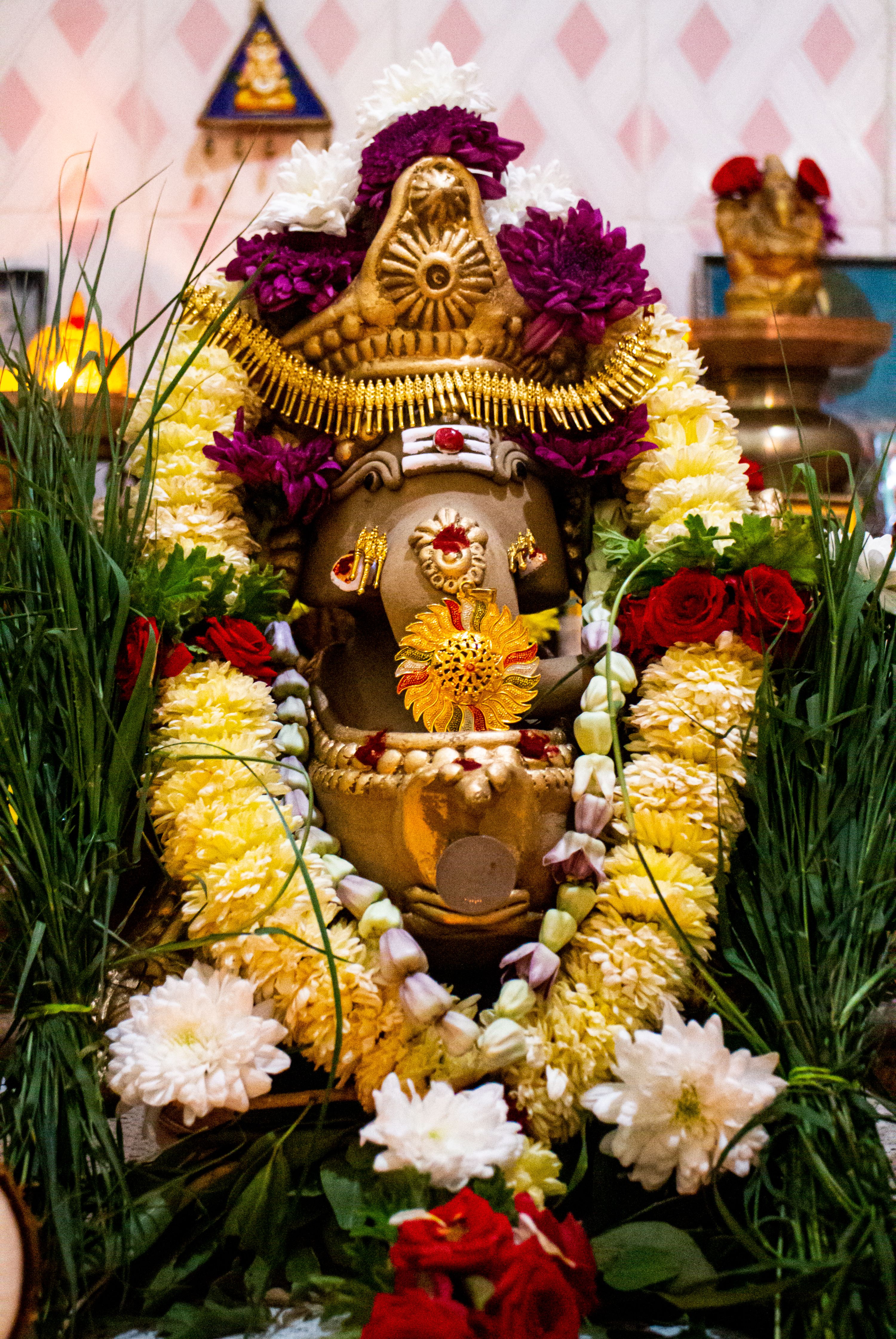 Intricate Ganesha statue in Bengaluru with colorful floral garland, depicting Hindu culture.