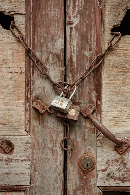 Close-up of Wooden Door with Rusty Chains and Padlocks 