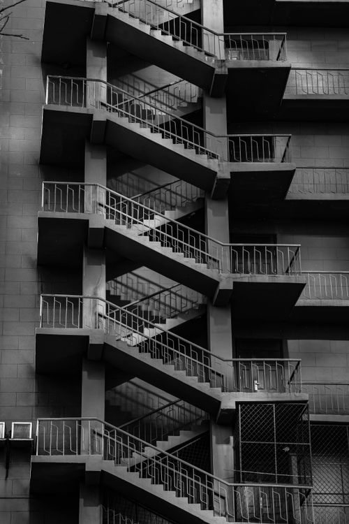 Free Vertical shot of an exterior spiral staircase in grayscale, showcasing urban architecture Stock Photo