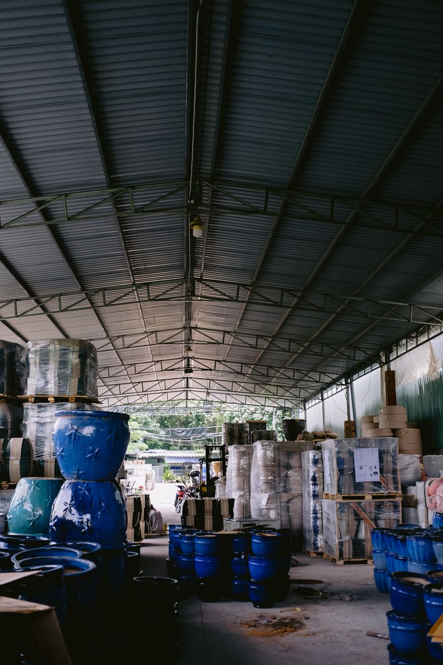 Interior view of a spacious warehouse featuring blue pots and various packed merchandise in a well-organized layout.