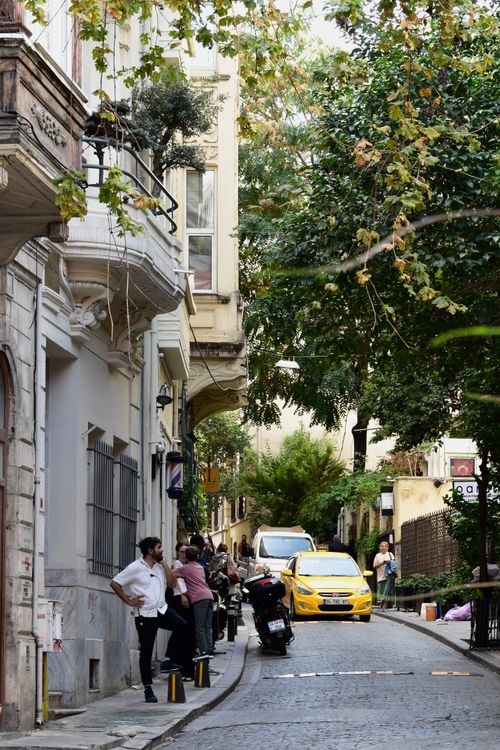 Free Peaceful urban street scene featuring a yellow taxi, people, and lush greenery. Stock Photo