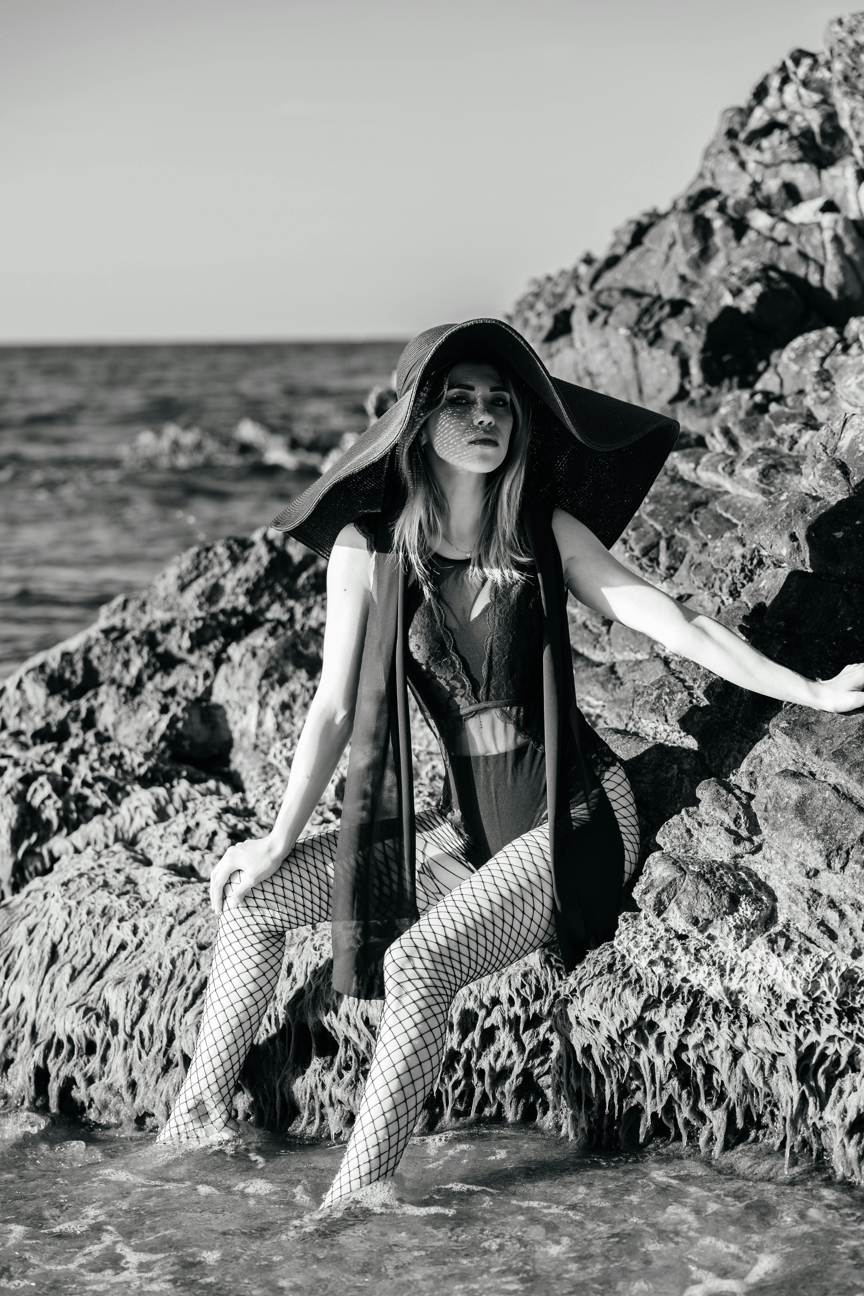 a woman sitting on rocks in the ocean