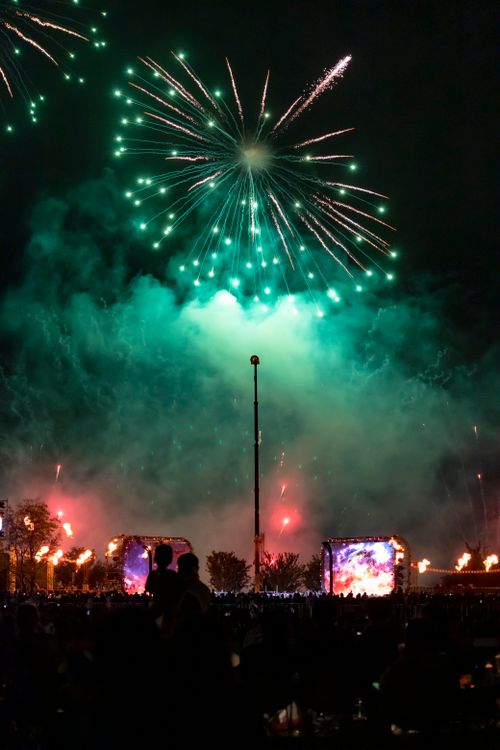 Free Vibrant fireworks light up the night sky during an urban celebration with a crowd watching. Stock Photo