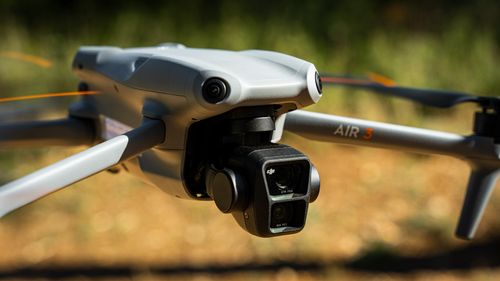 Free A detailed close-up of the DJI Air 3 drone camera in flight, showcasing its advanced design. Stock Photo