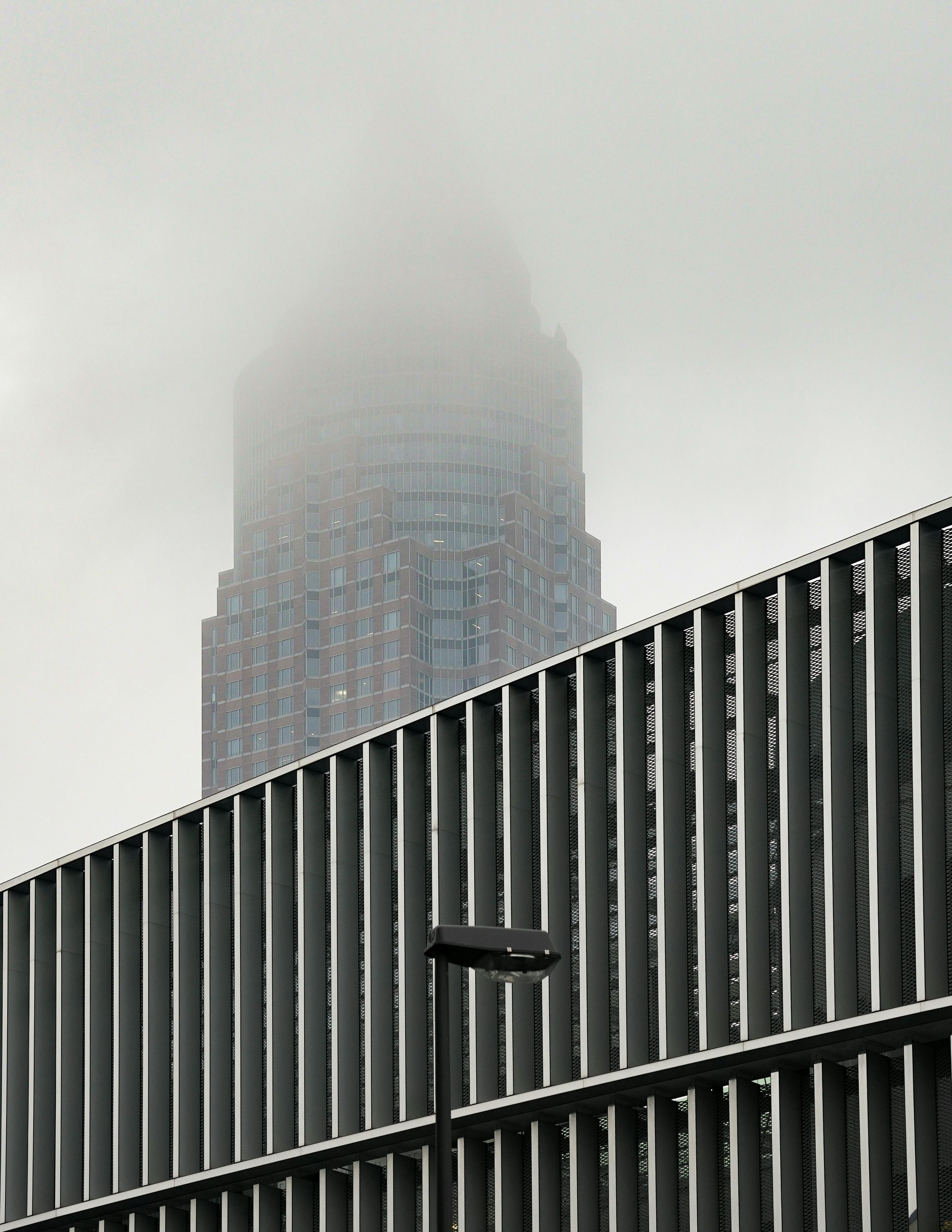 A skyscraper's peak disappears into the fog, highlighting urban architecture in a modern setting.