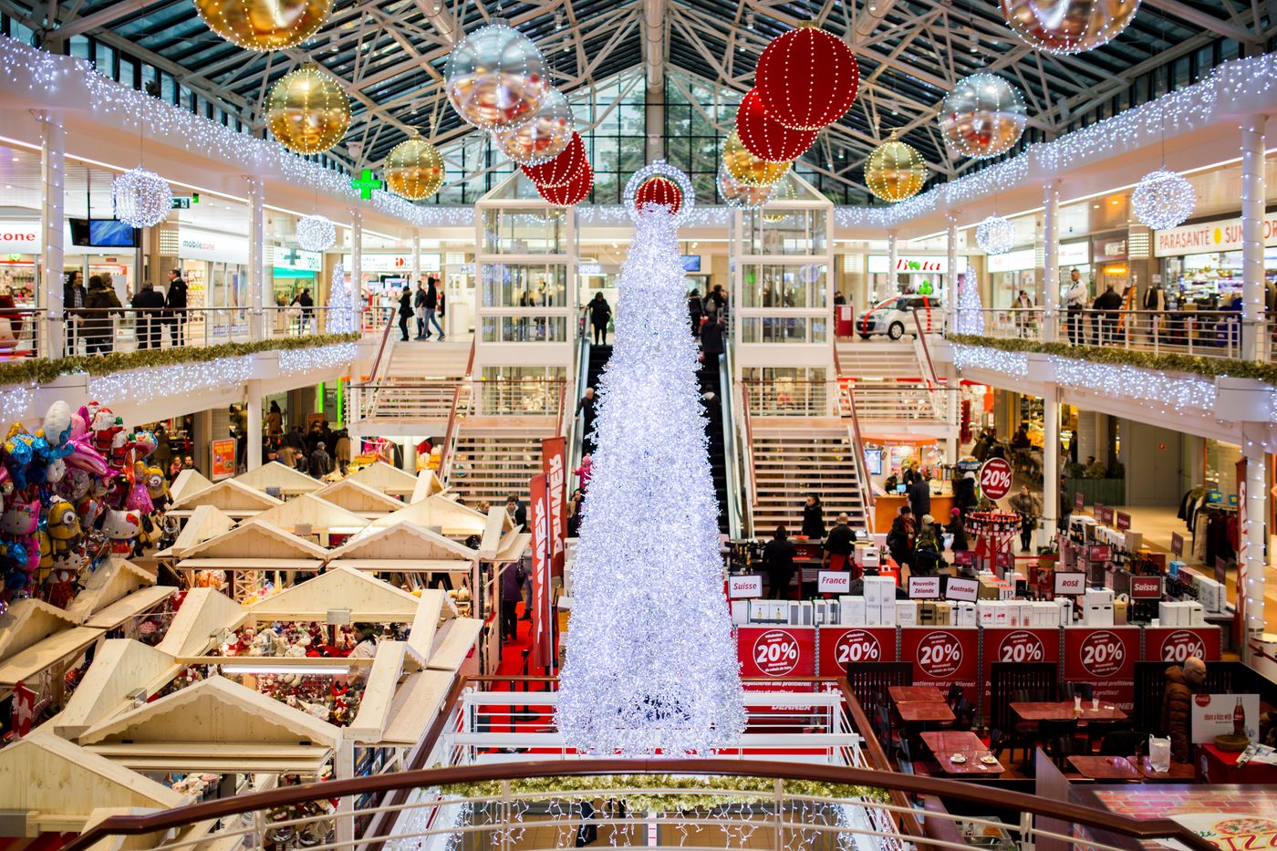 Busy shopping mall decorated for Christmas with shoppers walking between stores