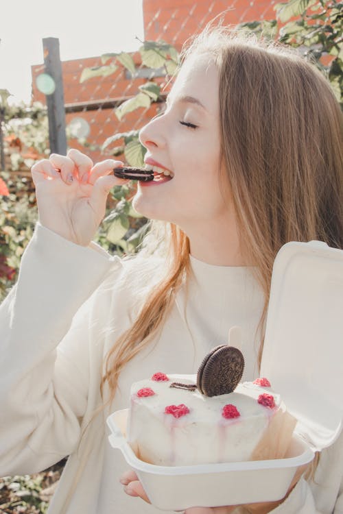 Woman Holding and Eating Cookie from Cake