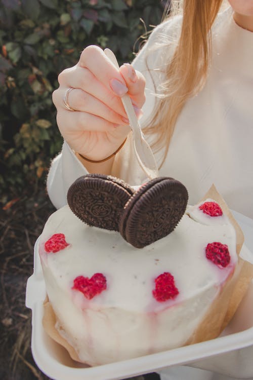 Woman Hand Holding Spoon over Cake with Cookies