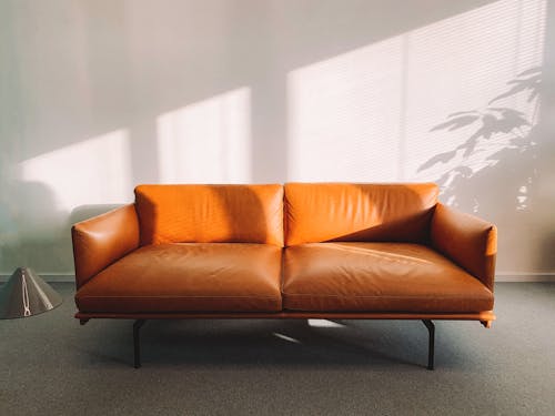  2-seat Orange Leather Sofa Beside Wall