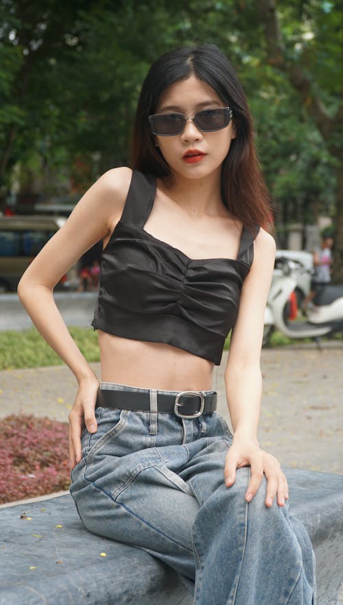 Woman in Black Top and Sunglasses Sitting on Bench in Park