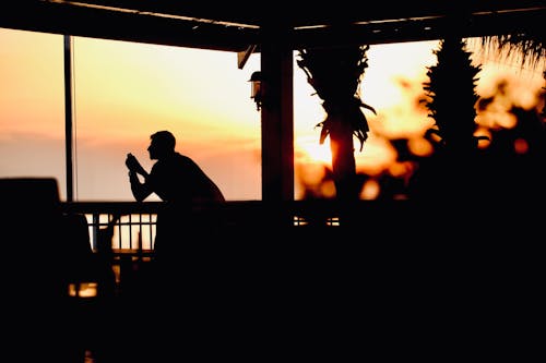 Silhouette of a Tourist in a Restaurant by the Tropical Sea at Sunset