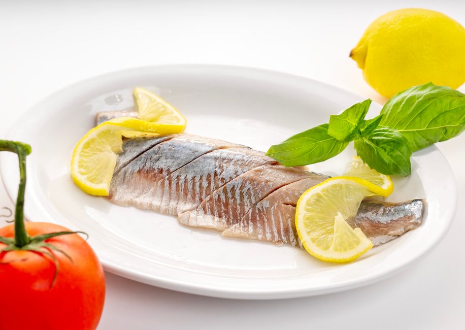 Delicious fresh fish fillet garnished with lemon slices and basil, served on a white plate.
