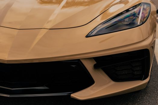 Detailed close-up of a luxury sports car's front in metallic gold, highlighting its sleek design.