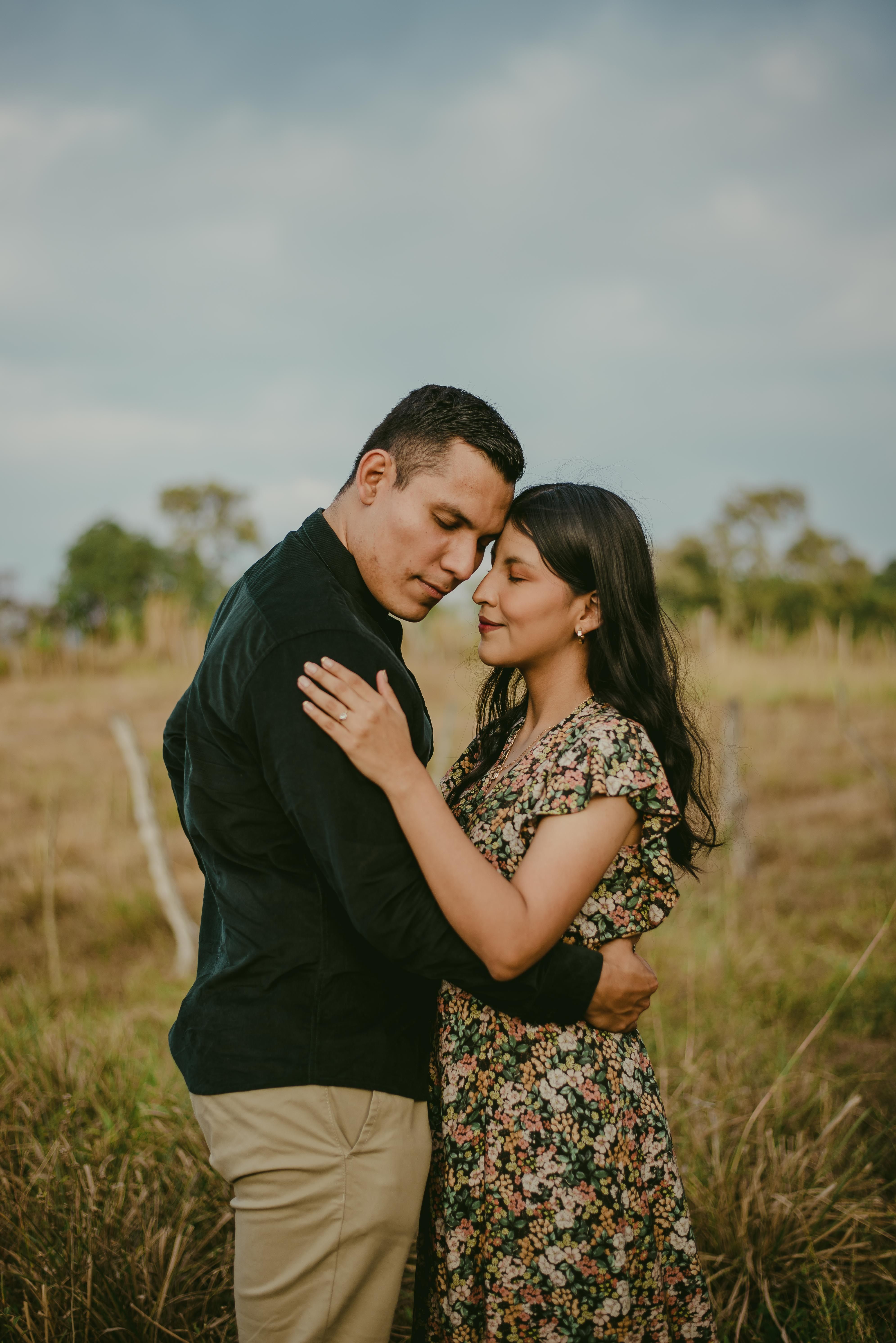 A Couple Standing on a Grass Field and Hugging · Free Stock Photo