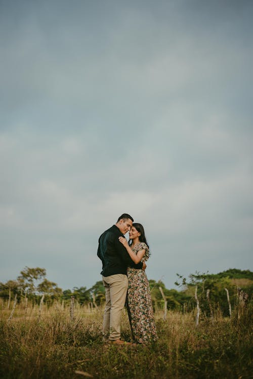 A Couple Standing on a Grass Field and Hugging 