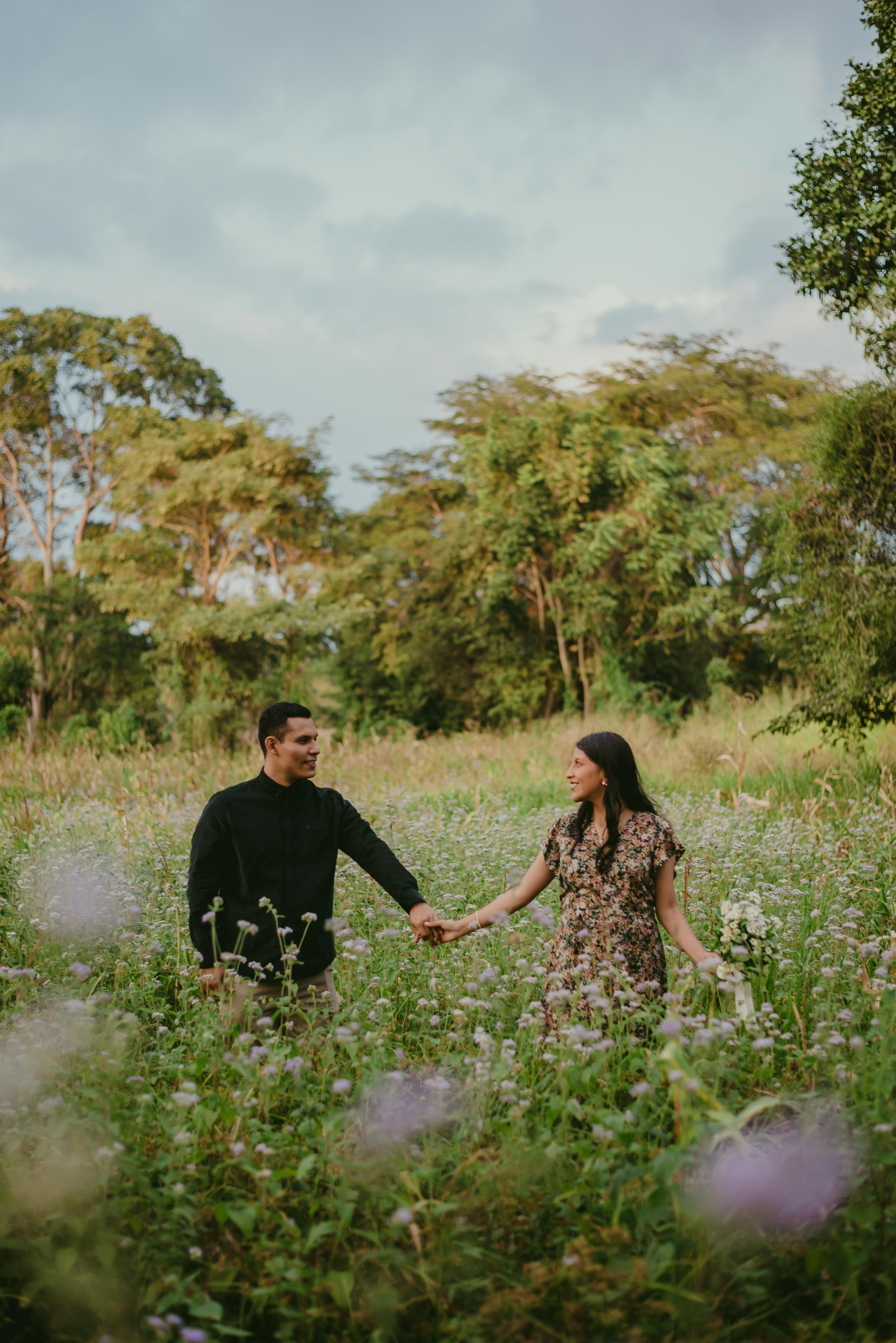 A Couple Standing on a Grass Field and Holding Hands · Free Stock Photo