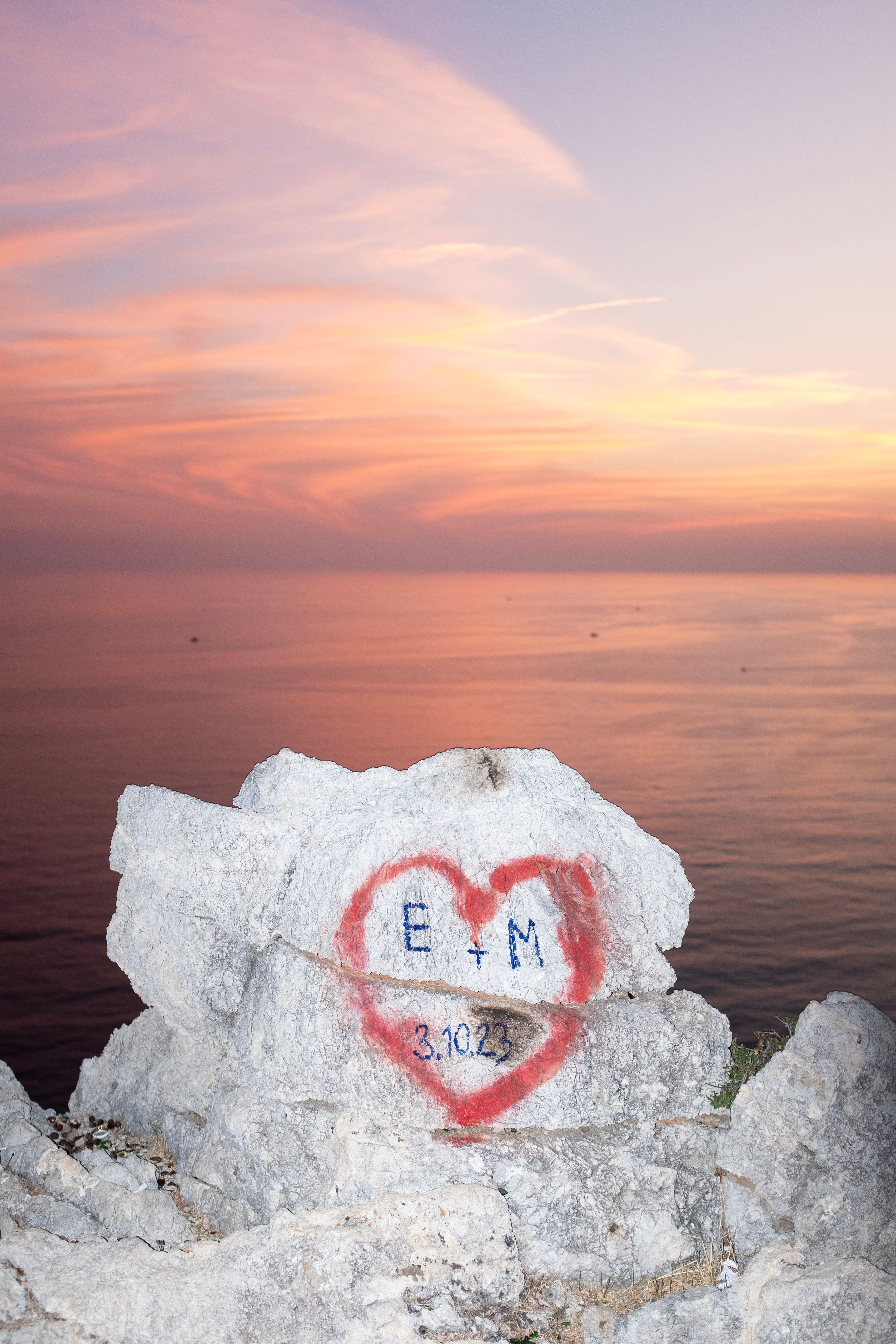 Heart-shaped graffiti on rocks at sunset by the sea in Alanya, Türkiye, symbolizing love.