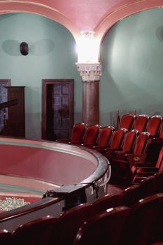 A beautifully illuminated theater interior showcasing red seats and classic architectural details.