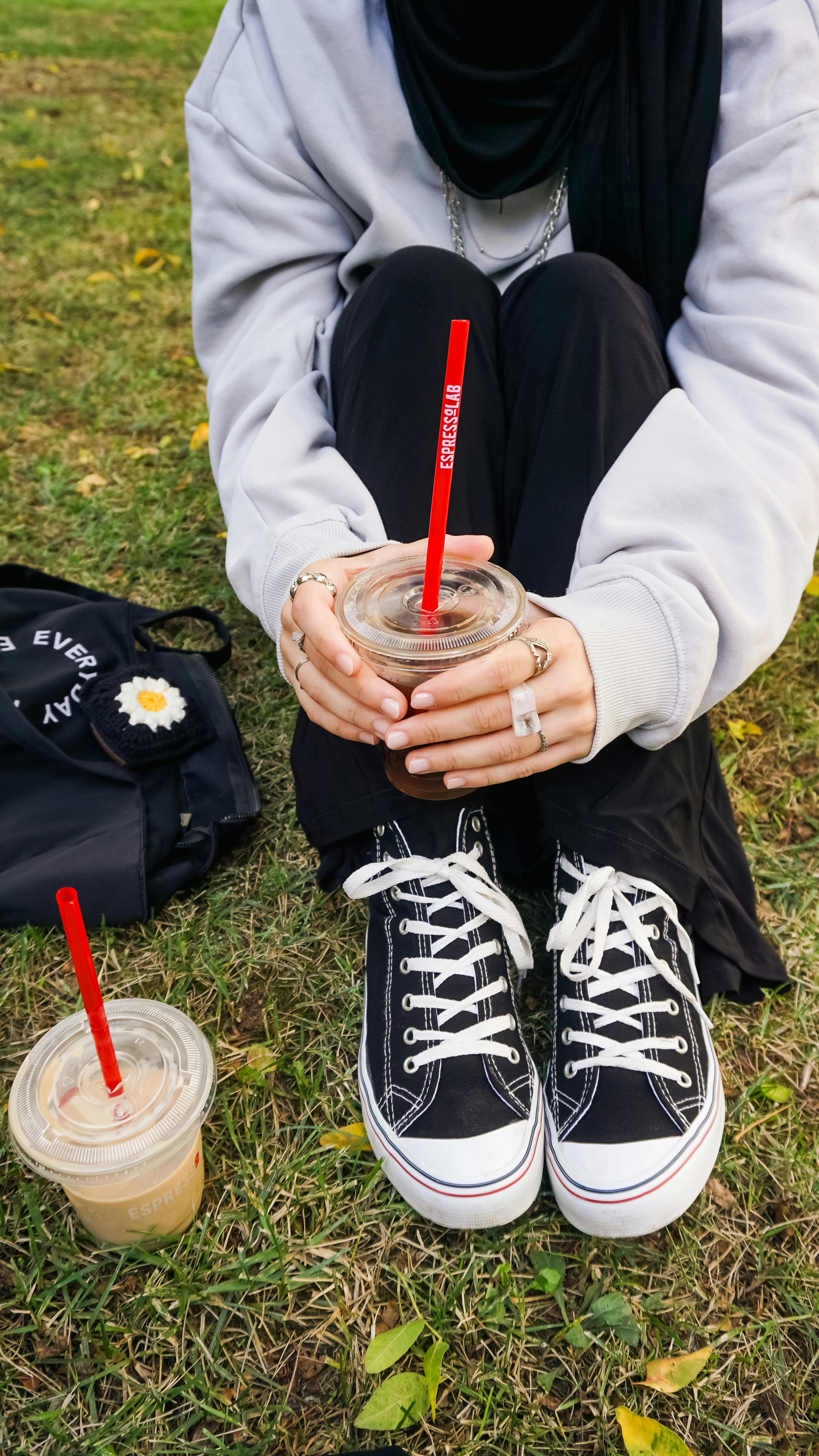 A Woman Sitting on a Bench Holding a Coffee Paper Cup · Free Stock Photo