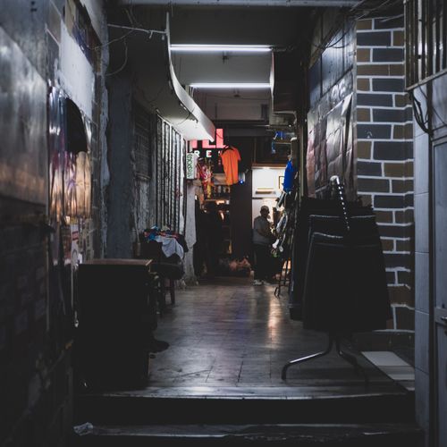 Free A narrow, dimly lit alleyway showcasing urban storefronts and merchandise displays. Stock Photo