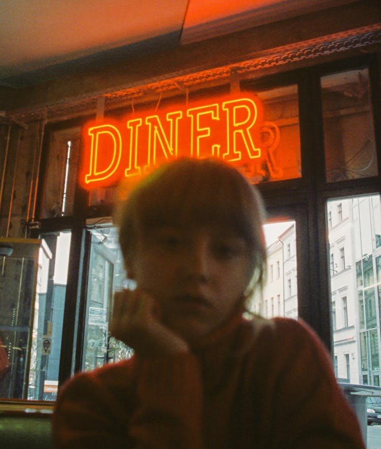 Neon Diner Sign Above Young Woman In The Restaurant