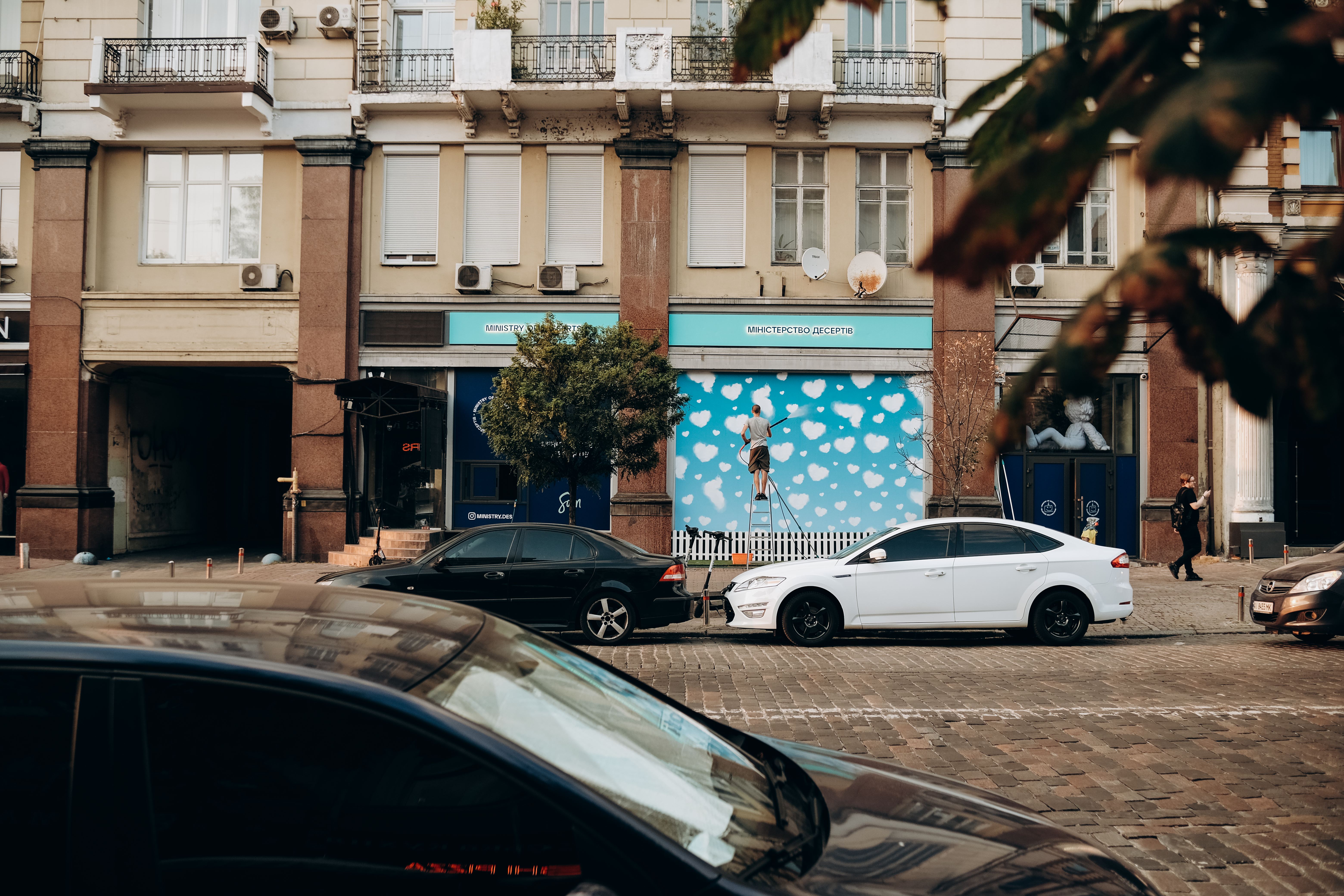 Urban street view in Kyiv showcasing parked cars in front of decorated buildings.