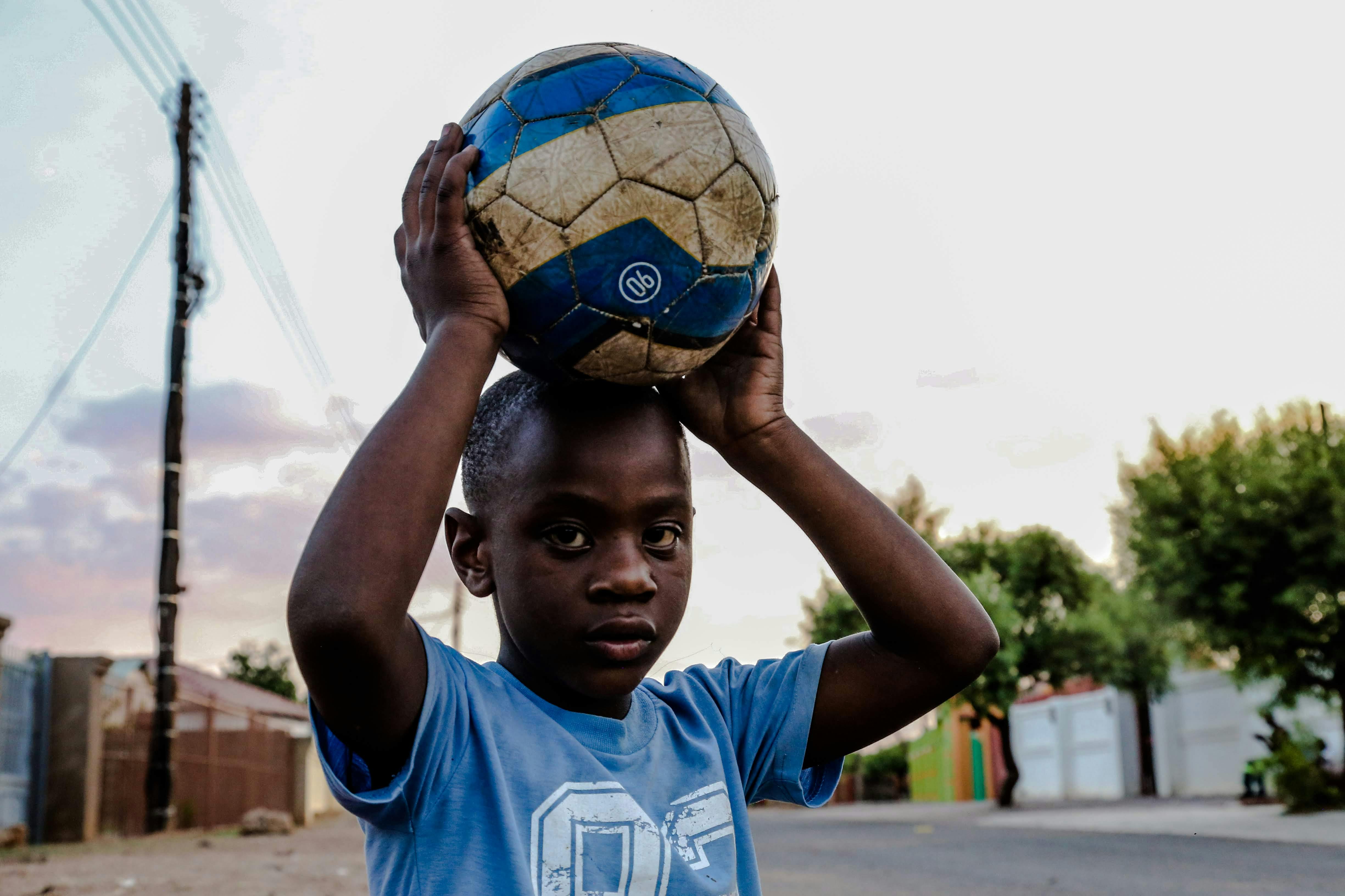 boy carrying soccer ball on his head