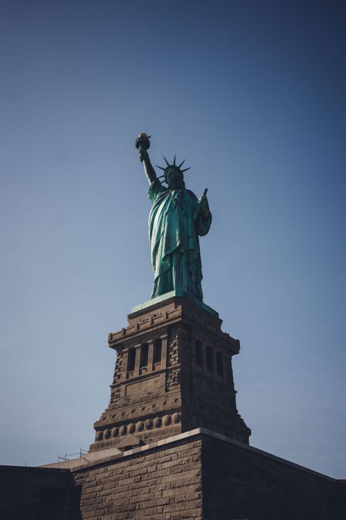 Free The iconic Statue of Liberty rises against a clear blue sky, symbolizing freedom in New York City. Stock Photo