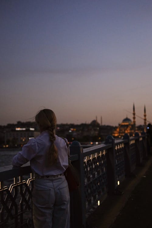 A woman is looking at the sunset from a bridge