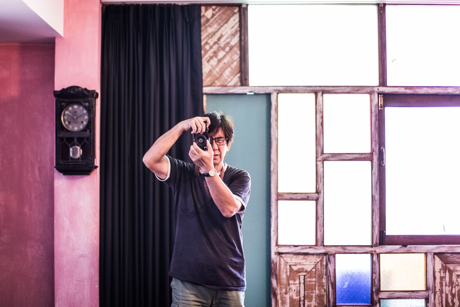 Male photographer taking a picture in a colorful room with vintage decor in Bangkok.