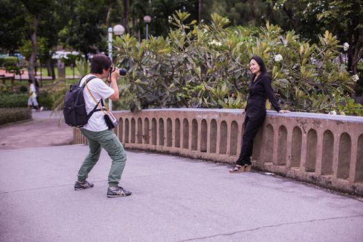 Photographer captures woman posing on bridge in Bangkok park.