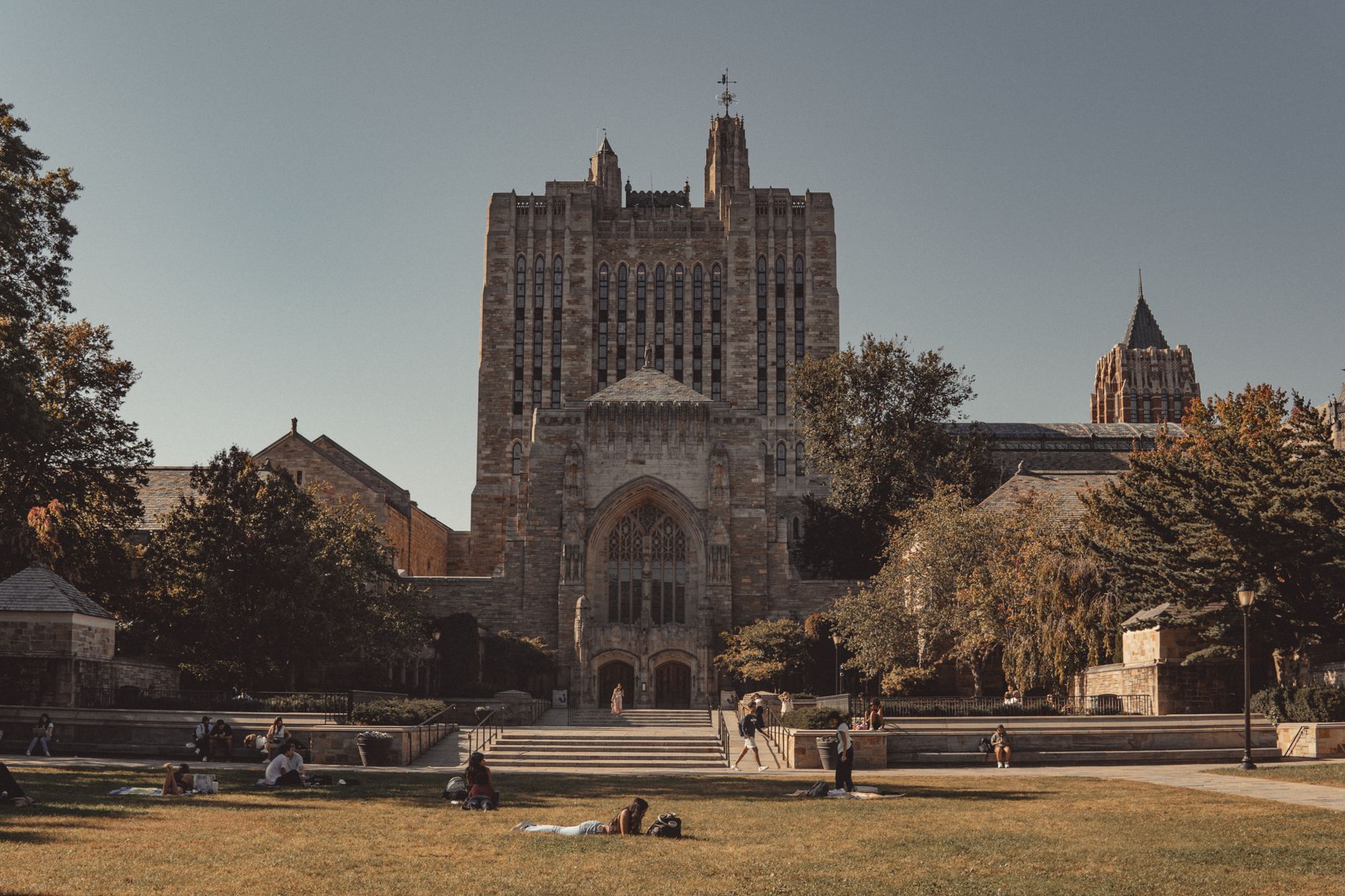 View of Yale University's neoclassical architecture with lawns and students relaxing outdoors.