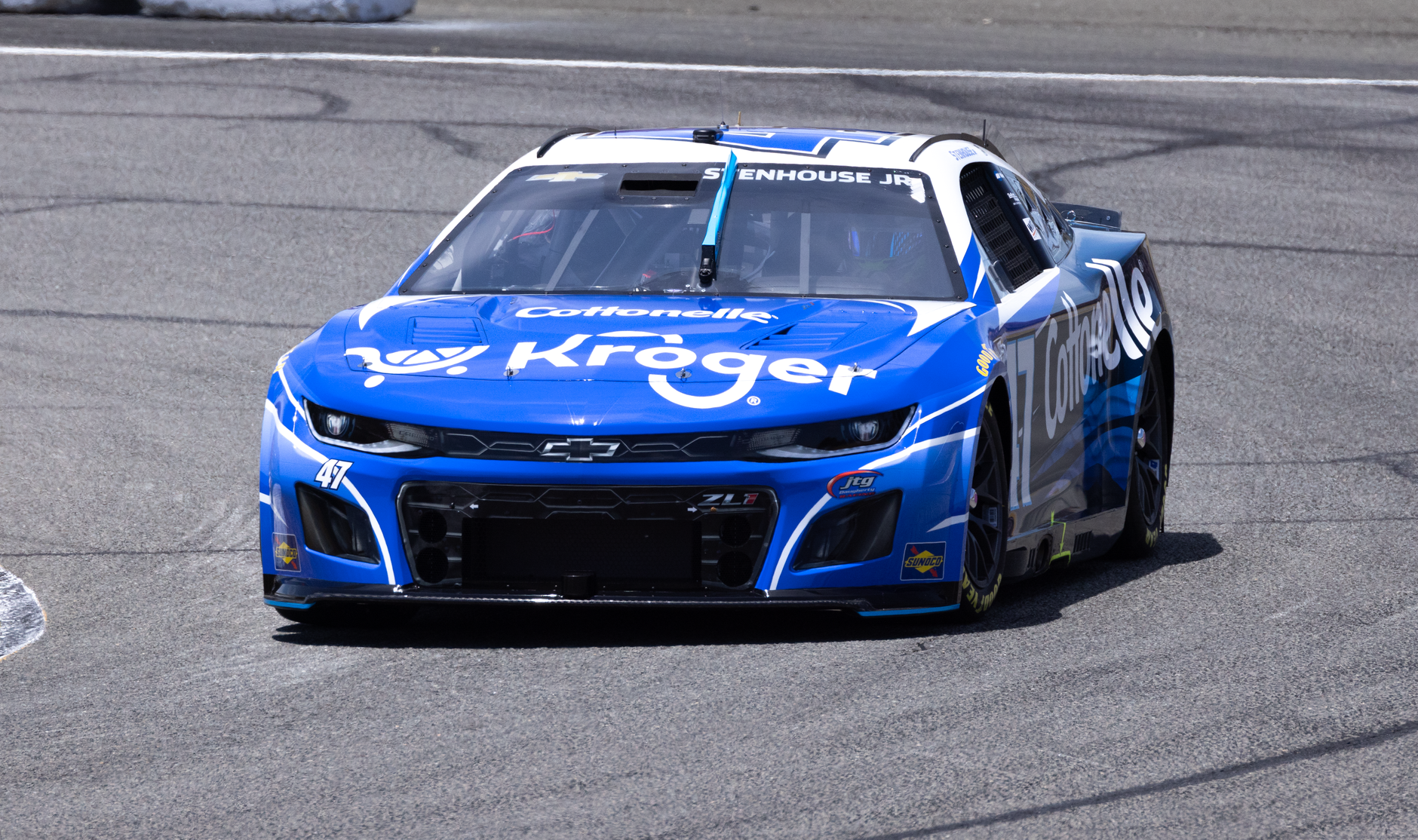 Capture of a blue NASCAR race car at high speed on an asphalt track, showcasing dynamic racing action.