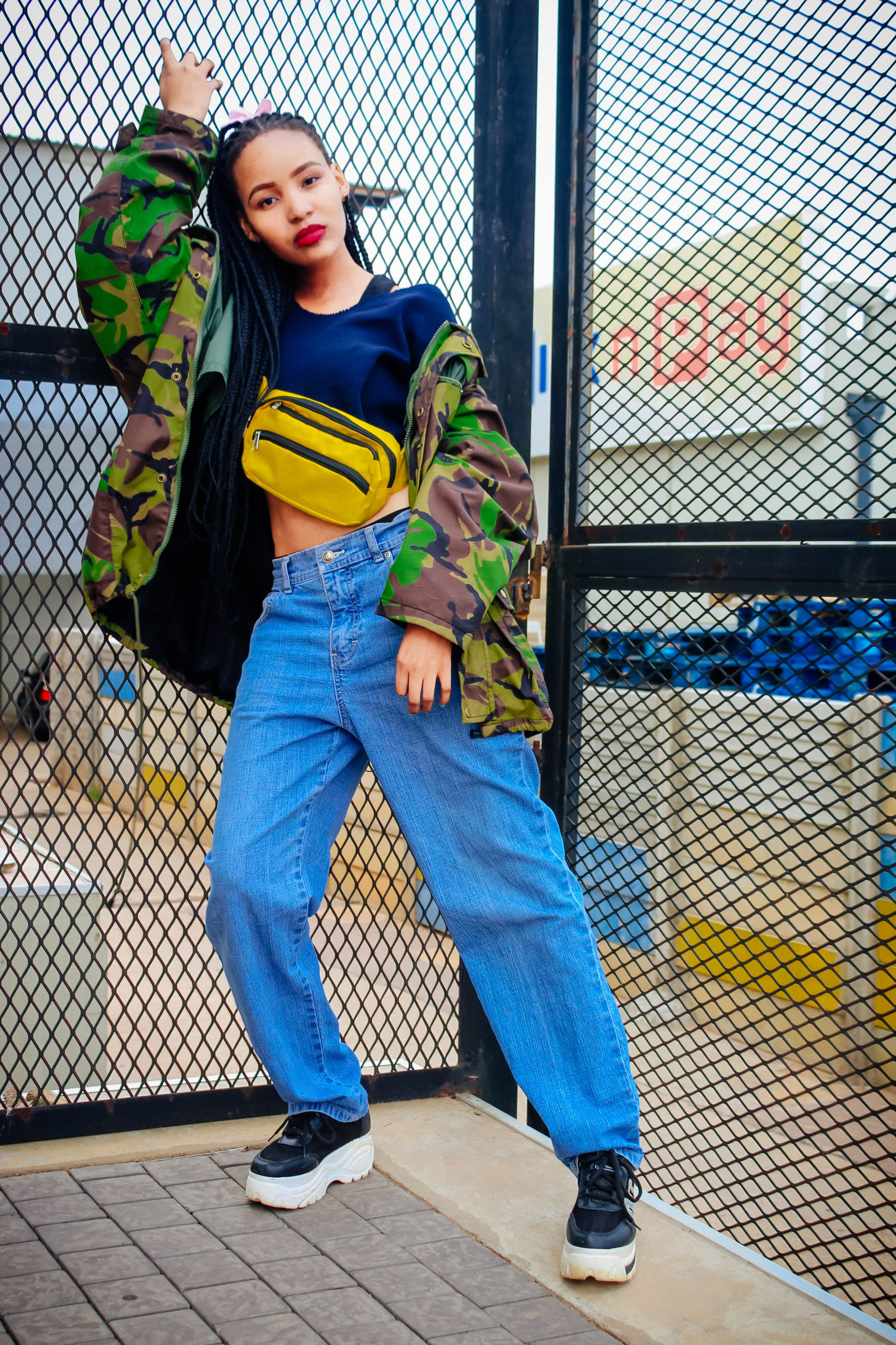 Mulher fashion em ambiente urbano com jaqueta camuflada e jeans.