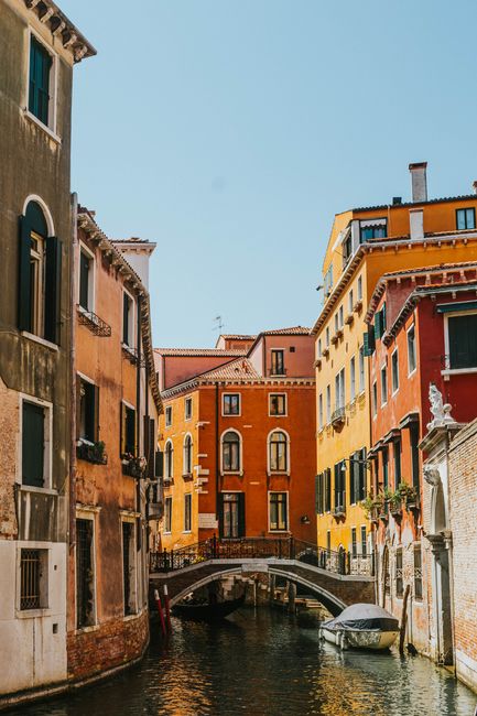 A picturesque view of a Venetian canal framed by vibrant buildings and a charming bridge.