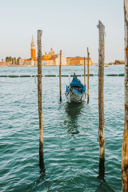 A picturesque view of a gondola moored in Venice, Italy, with historic architecture in the background.