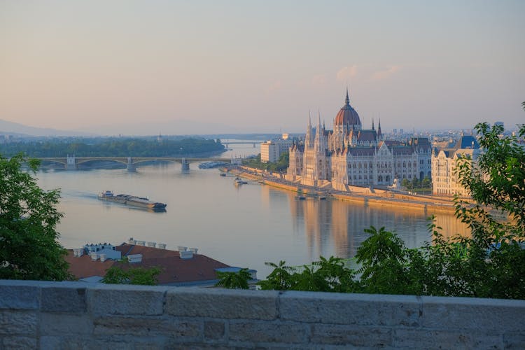 Hungarian Parliament Building By The Danube River In Budapest At Sunset