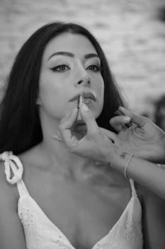 Brunette model getting makeup applied by artist in black and white photo.