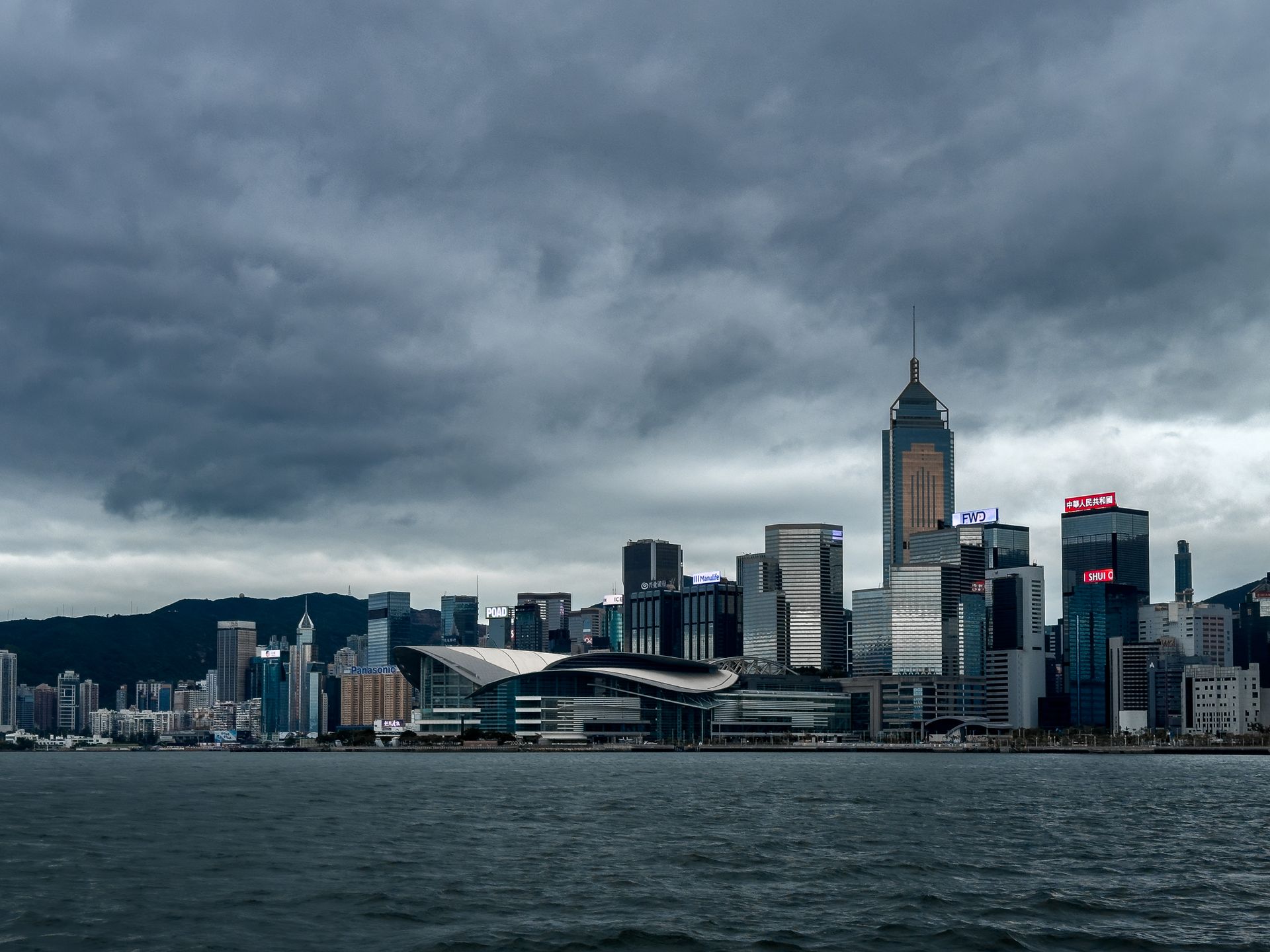 Silhouette du port de Hong Kong sous un ciel couvert, reflétant la tension du hub.