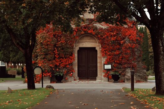 A historic Swedish building adorned with vibrant red autumn leaves in Jönköping.