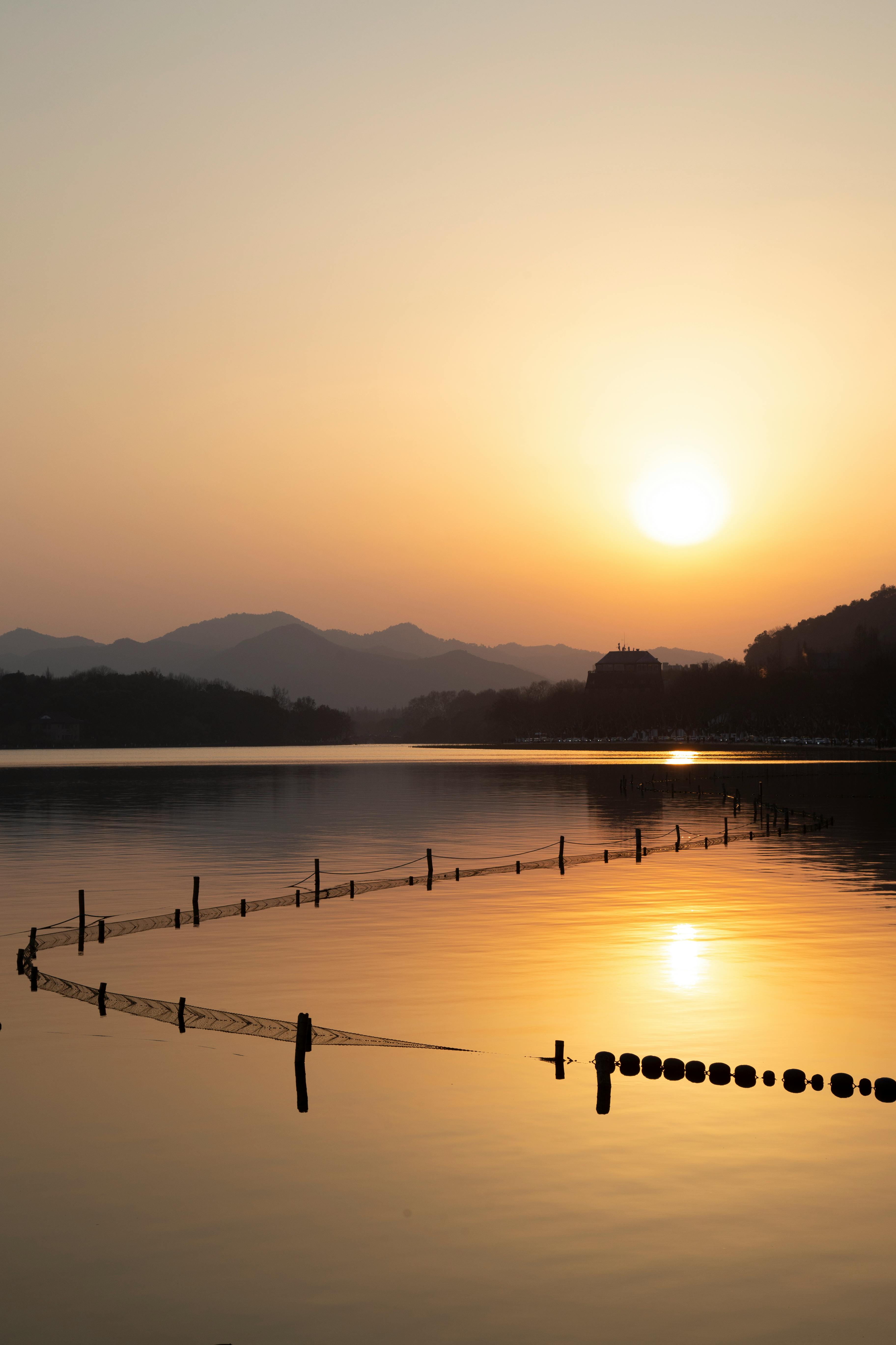 A beautiful sunset over a calm lake with mountains and reflections, creating a peaceful scene.