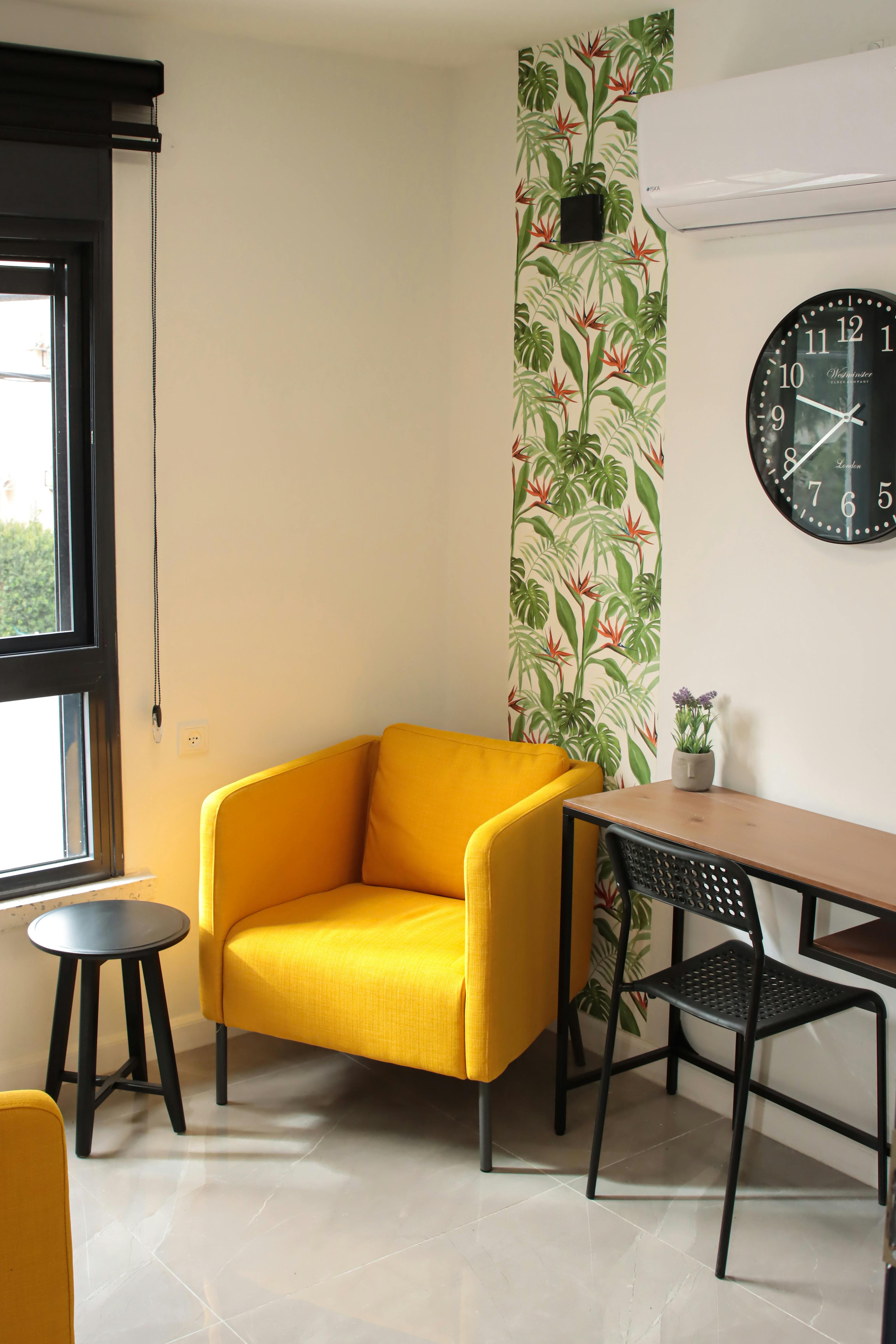 Cozy room with yellow armchair, desk, and decorative wall clock.