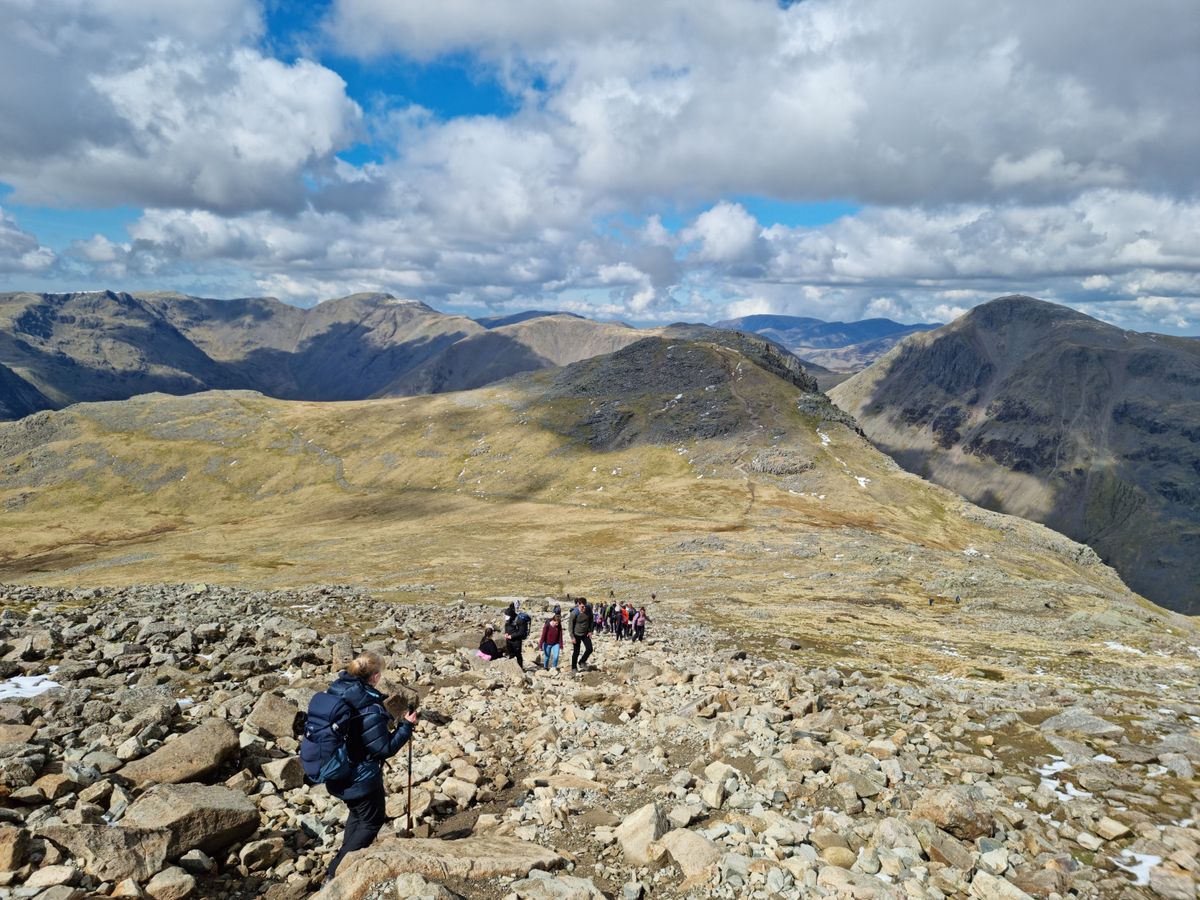 A group descending a rocky boulder field high on the fells.