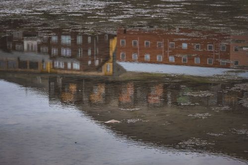 Free Captivating reflection of brown brick buildings mirrored in a calm water surface. Stock Photo