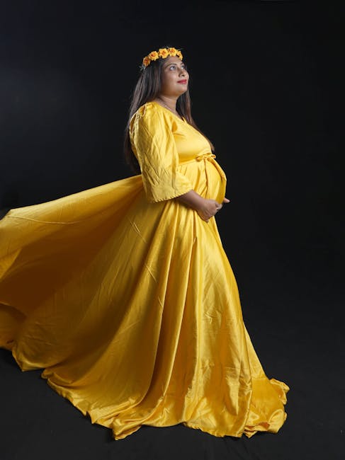 A captivating maternity portrait of a woman in a flowing yellow dress and flower crown.