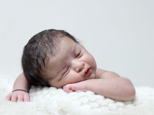 Free A serene image of a newborn baby sleeping on a soft white blanket, capturing innocence and tranquility. Stock Photo
