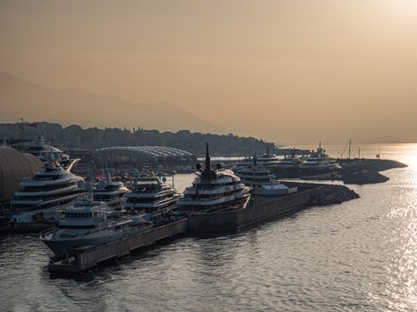 A peaceful sunrise view of luxury yachts moored at Genoa harbor, Italy.