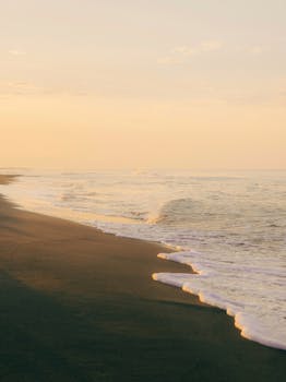 A serene beach scene featuring early morning waves and golden sunrise colors for a peaceful start to the day.