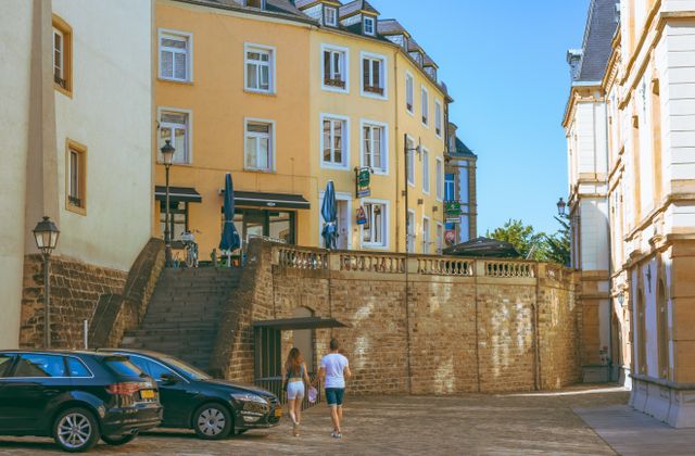 A couple walks along a picturesque street in Luxembourg City, showcasing historic architecture and urban charm. — arriving in Luxembourg
