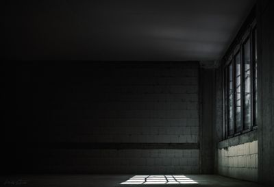 Dimly lit industrial space with concrete walls and large window castin — Photo by Average GUY on Pexels